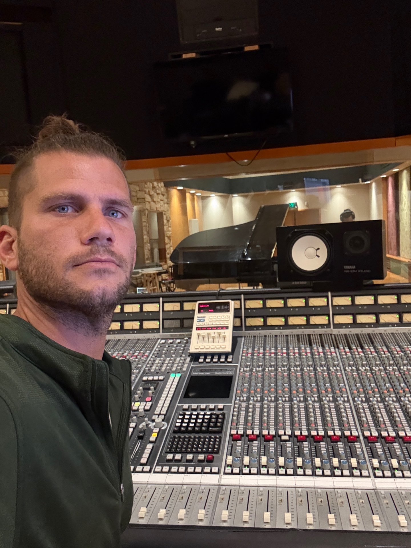 Dimly lit recording studio control room with a large mixing console glowing under amber light